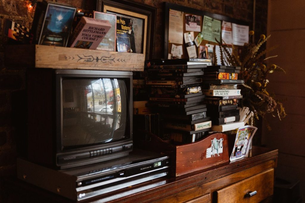 Retro television, VCR and stacked VHS tapes on a wooden dresser