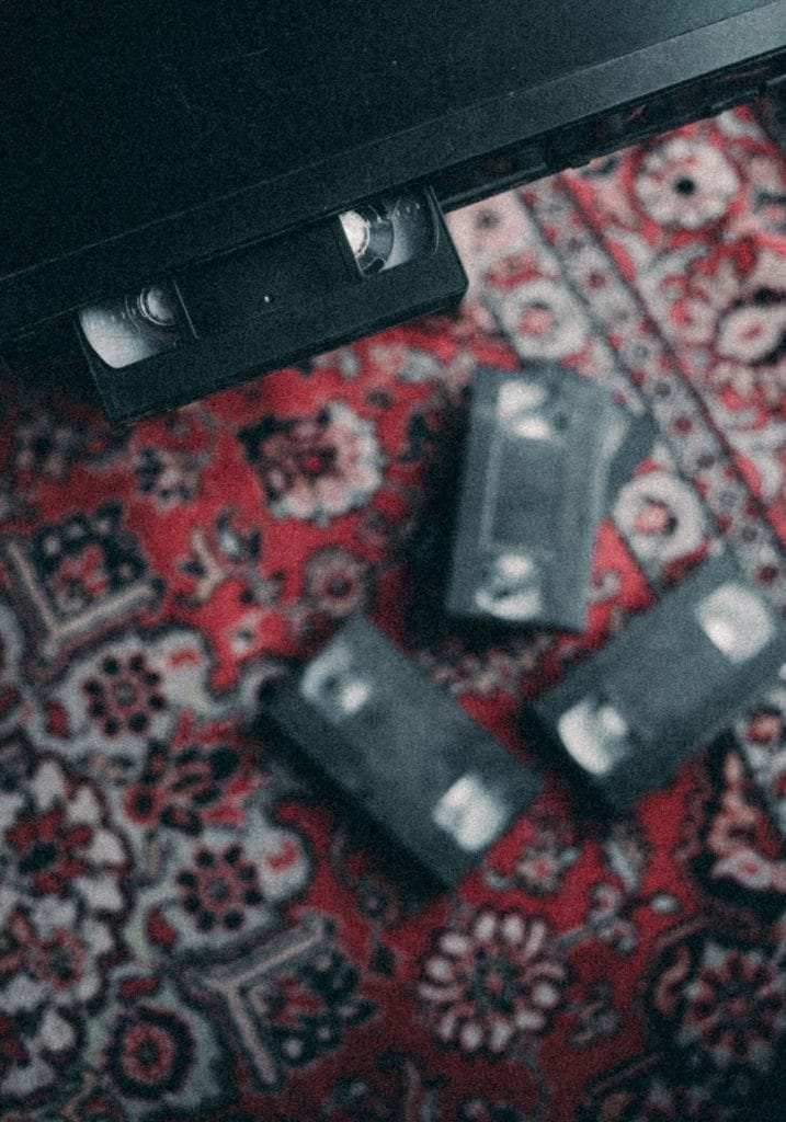 Retro VHS video cassettes arranged on a colorful patterned carpet