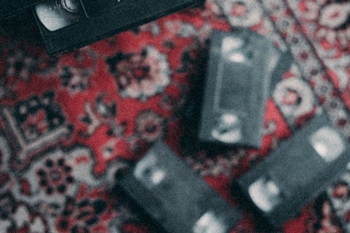 Retro VHS video cassettes arranged on a colorful patterned carpet